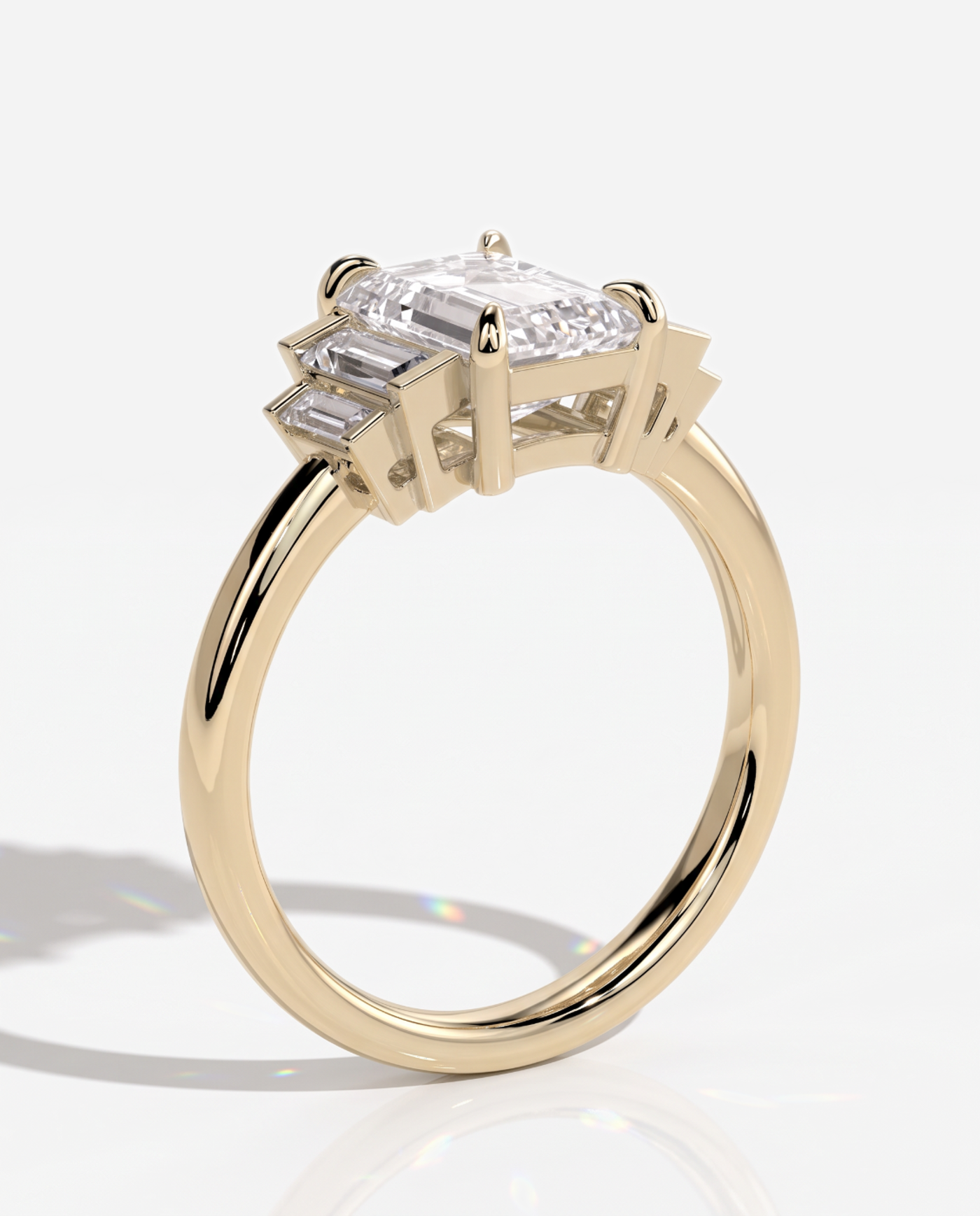 Hannah Emerald Claw Trilogy with Graduating Baguette Shoulder Stones Engagement Ring, lab grown diamond in yellow gold, three quarter view